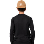 A child viewed from behind wearing a black long-sleeve shirt and a tan New York Yankees baseball cap with a white embroidered NY logo, set against a plain white background.