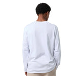 A person shown from the back wearing a plain white long-sleeve t-shirt and light beige pants against a solid white background.