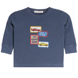 A toddler's long-sleeve waffle-knit shirt in slate blue, featuring three colorful graphic patches on the chest with cars and text reading 'BORN TO RIDE' and 'no speed limit'.