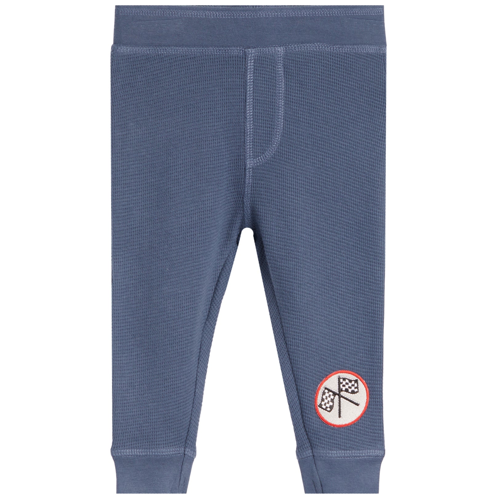 A pair of kids' blue waffle-knit pants with a small circular graphic patch on the lower left leg, shown against a plain white background.