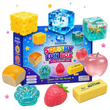 Squishy Fun Box sensory toy set with a blue retail box and multiple toy pieces including a yellow cheese cube, translucent blue ice cubes, a pink apple, a bread loaf, a strawberry, butter, and other textured food-like shapes, arranged on a white background with small star confetti.