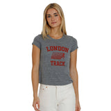 A woman modeling a heather gray cropped t-shirt with a red distressed 'LONDON TRACK' graphic on the front, paired with white pants, against a plain white background.