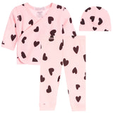 A three-piece baby clothing set including a long-sleeve wrap top, matching pants, and a beanie hat, all in light pink with a black heart pattern, displayed on a solid white background.