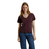 A woman modeling a short-sleeve V-neck t-shirt in a deep burgundy color, paired with blue jeans, against a plain white background.