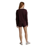 A woman shown from the back wearing a matching dark burgundy long-sleeve top and shorts set, paired with white sneakers, against a plain white background.