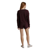 A woman shown from the back wearing a matching dark burgundy long-sleeve top and shorts set, paired with white sneakers, against a plain white background.