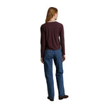 A woman shown from the back wearing a dark burgundy long-sleeve shirt and blue jeans, standing against a plain white background.
