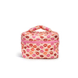 A small quilted cosmetic bag with a top handle, featuring an allover pink and red lip print on a light peach background, with a pink zipper closure.