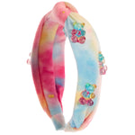 A plush headband with a pastel tie-dye pattern in pink, blue, yellow, and orange, decorated with three colorful teddy bear embellishments, shown on a plain white background.