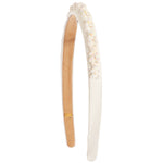 An off-white fabric headband with a ruffled trim, decorated with small white and iridescent floral beads along one side, and a tan adjustable inner band with a small gold metal clasp.