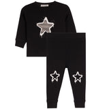 A toddler's two-piece black sweatshirt and jogger pants set. The long-sleeve sweatshirt features a large white and gray star graphic on the chest, while the matching jogger pants have two smaller white star graphics on the lower legs.