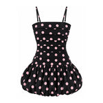 A black retro-style dress with pink polka dots, featuring a structured bustier top and a flared ruffled skirt, shown against a plain white background.