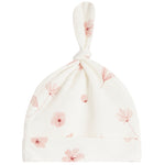 An off-white baby hat with a knotted top and a soft pink floral print, shown against a plain white background.