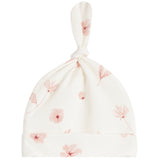 An off-white baby hat with a knotted top and a soft pink floral print, shown against a plain white background.