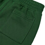 Close-up of dark green fabric showing an elastic waistband and a stitched side pocket, photographed on a white background.