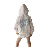 Young girl wearing a white hoodie and shorts set with pink floral patterns and blue 'happy camp' text on a white background