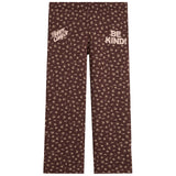 Brown pants with a beige floral pattern, featuring 'Happy Camp3r' on the left thigh and 'BE KIND!' on the right thigh, shown flat on a white background.