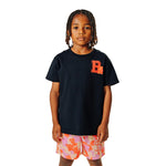 Child wearing a black t-shirt with an orange 'B' logo and colorful gummy bear patterned shorts on a white background