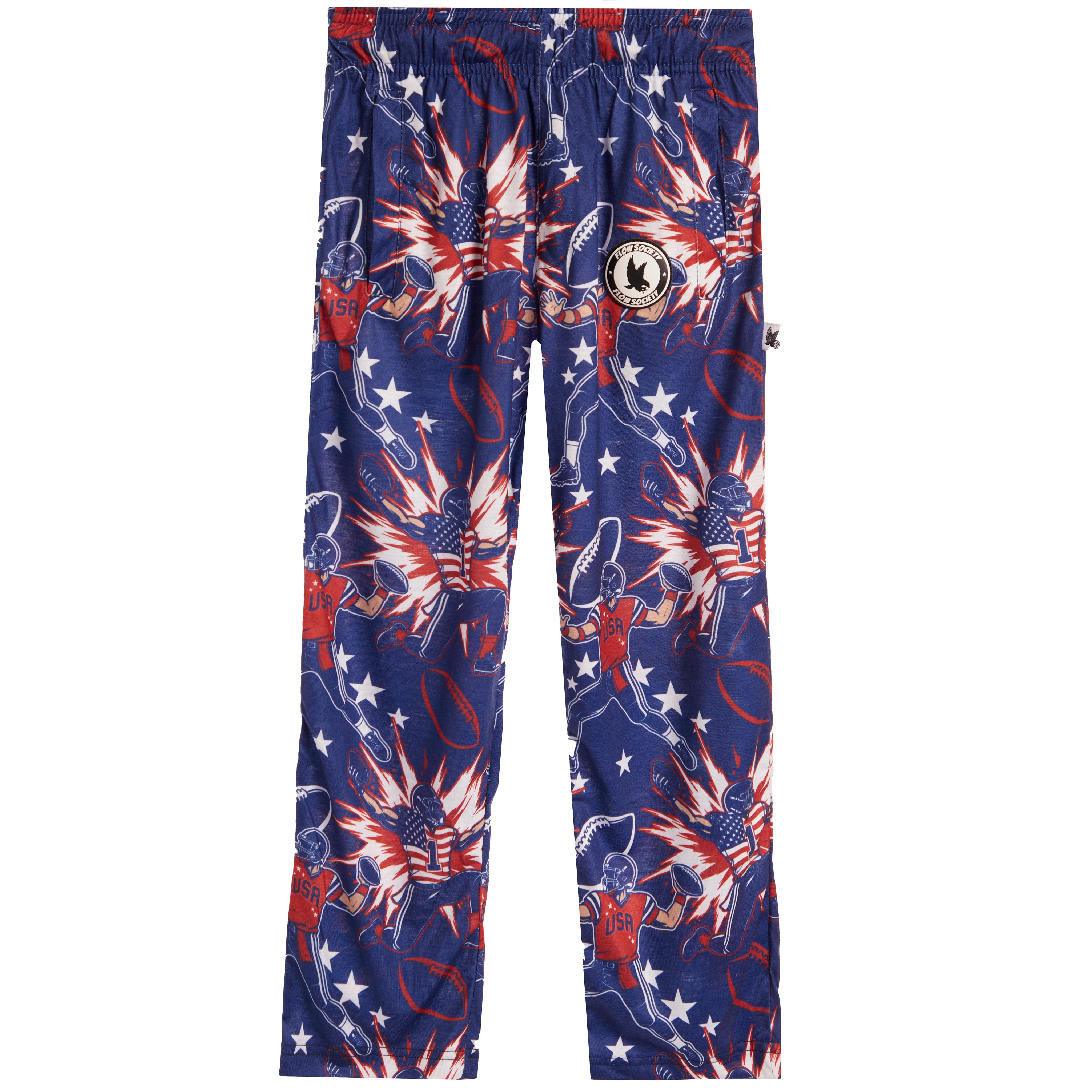 A pair of kids' pants featuring a patriotic American flag theme with stars, football players, and fireworks prints in navy blue, red, and white. A circular patch with a 'K' logo is visible on the left thigh.