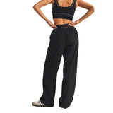 A model shown from the back wearing black athletic pants and a black sports bra with white trim, standing against a solid white background.