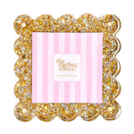 A square scalloped-edge photo frame filled with gold and silver glitter.