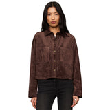A woman modeling a cropped brown suede button-up shirt jacket with two front patch pockets, paired with dark jeans, against a plain white background.
