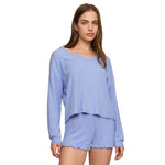 A woman modeling a light blue ribbed knit two-piece loungewear set consisting of a long-sleeve cropped top and matching shorts, set against a plain white background.