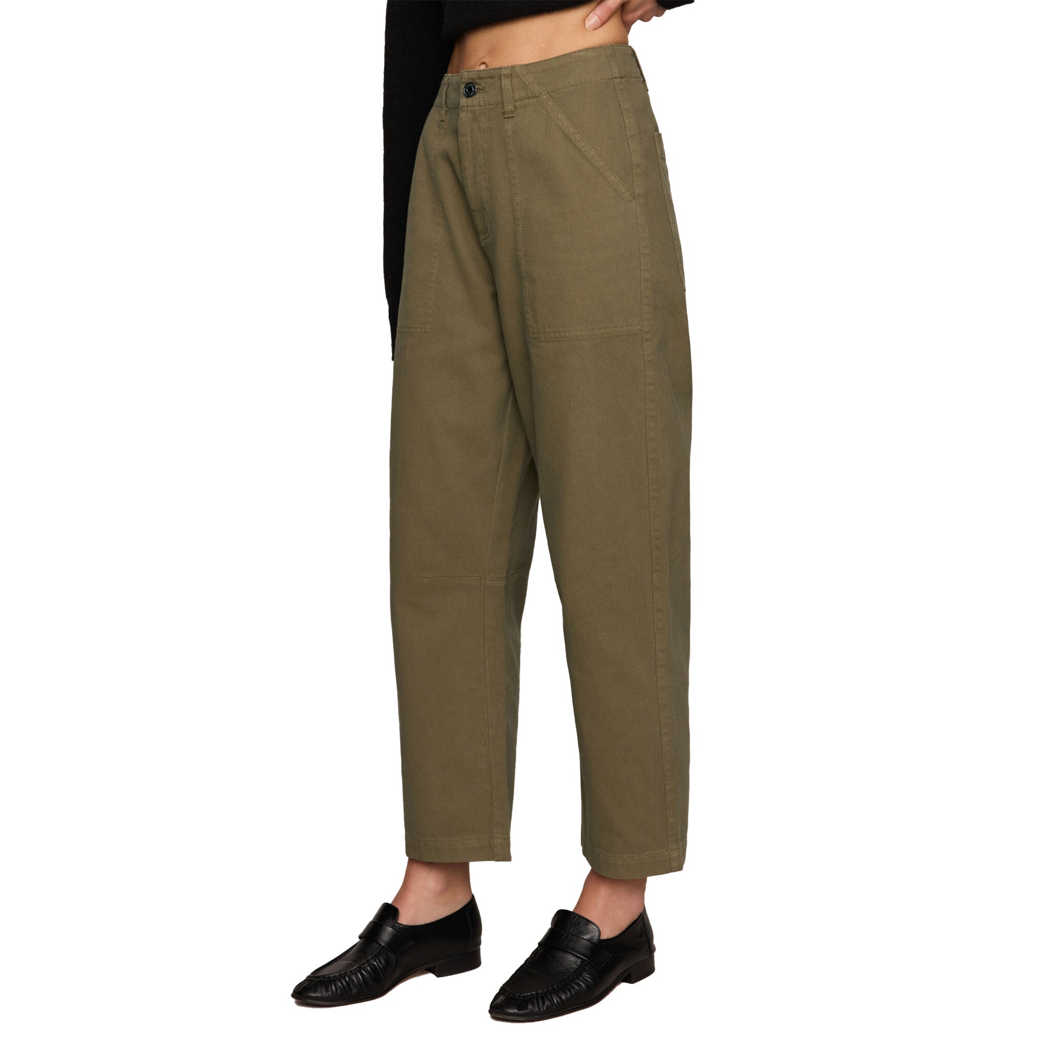 A person wearing loose, straight-leg cropped pants in an olive green color, paired with black loafers and a black cropped top, shown from the waist down on a white background.