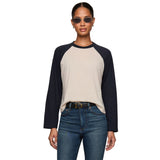 A woman modeling a long-sleeve raglan baseball tee with a light beige body and dark navy sleeves against a plain white background.