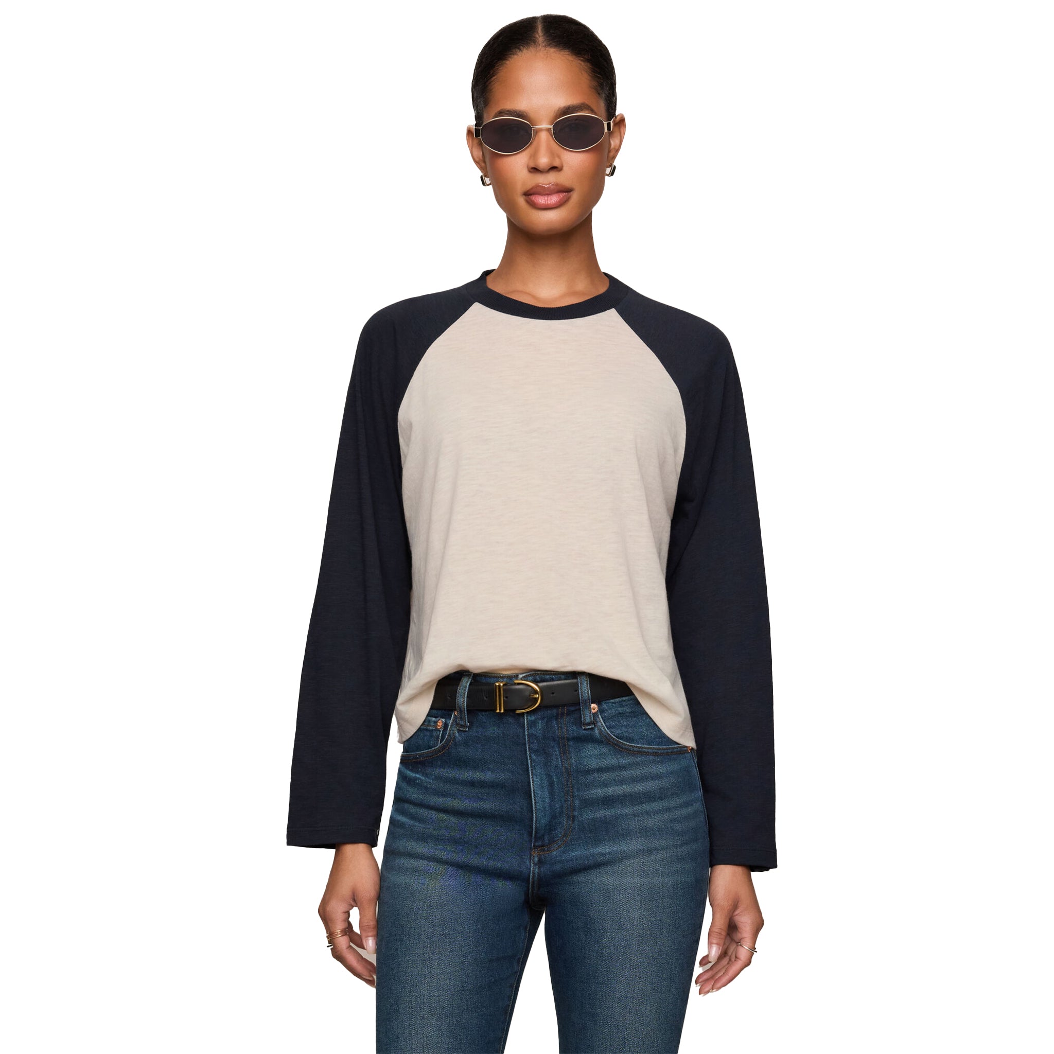 A woman modeling a long-sleeve raglan baseball tee with a light beige body and dark navy sleeves against a plain white background.