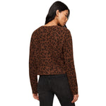 A woman shown from the back wearing a brown long-sleeve knit top with a black leopard print pattern against a plain white background.