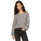 A woman wearing modeling a cropped, long-sleeve henley-style knit top in grey dark gray jeans against a plain white background.